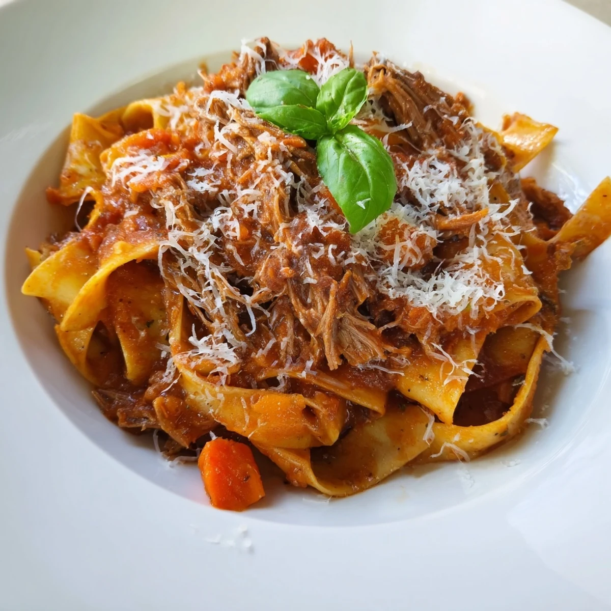 Slow Cooker Beef Ragu with Pappardelle Pasta is ladled generously over silky, wide noodles in a rustic white bowl.