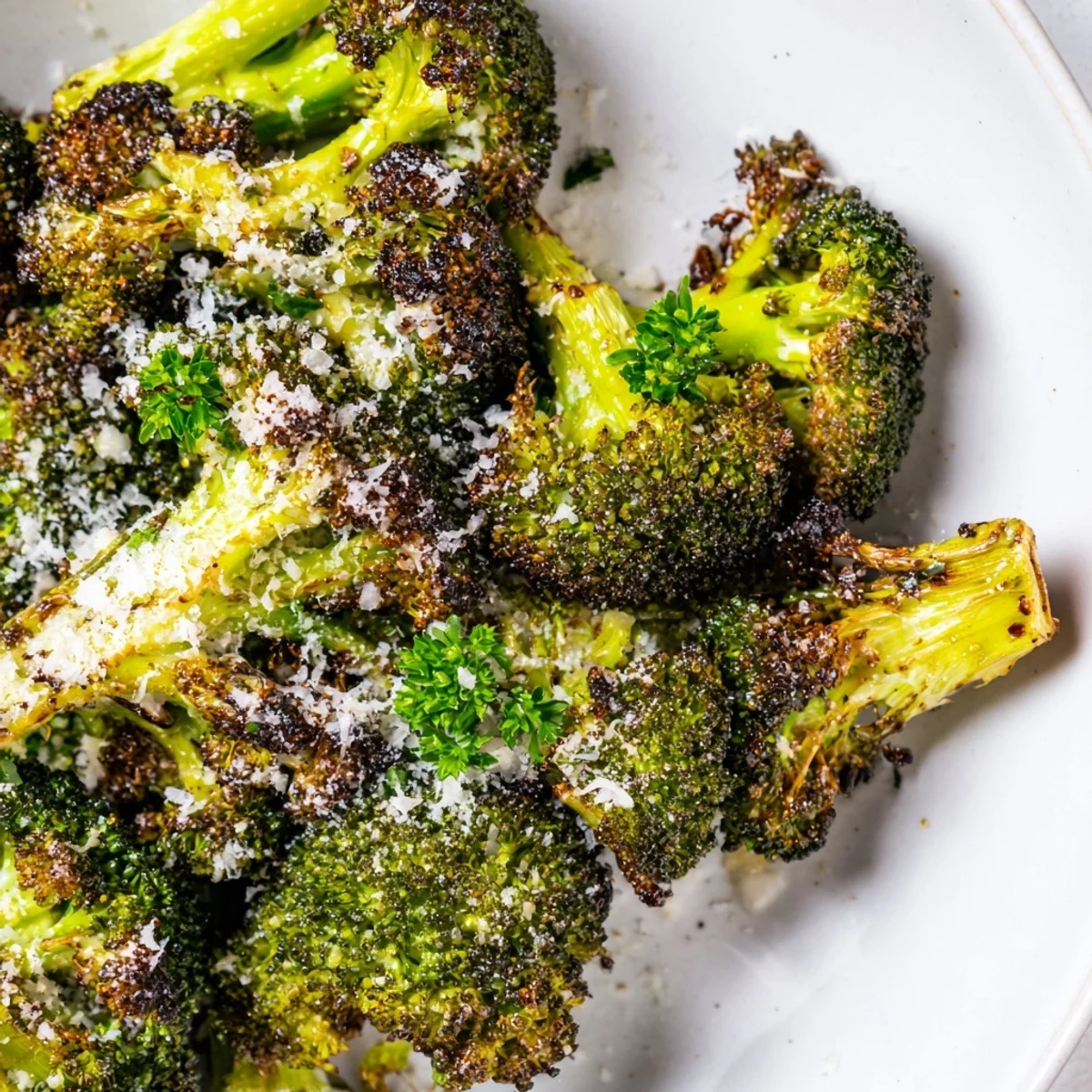 A close-up of Roasted Broccoli with Garlic and Parmesan Cheese showing crisp-tender florets with olive oil sheen and minced garlic specks.