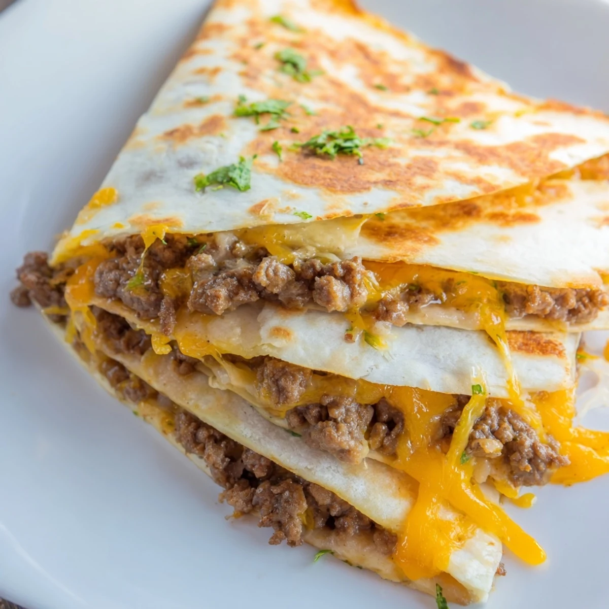 Golden-brown Cheesy Beef and Bean Quesadillas are sliced into wedges, revealing layers of seasoned ground beef and gooey melted cheese.