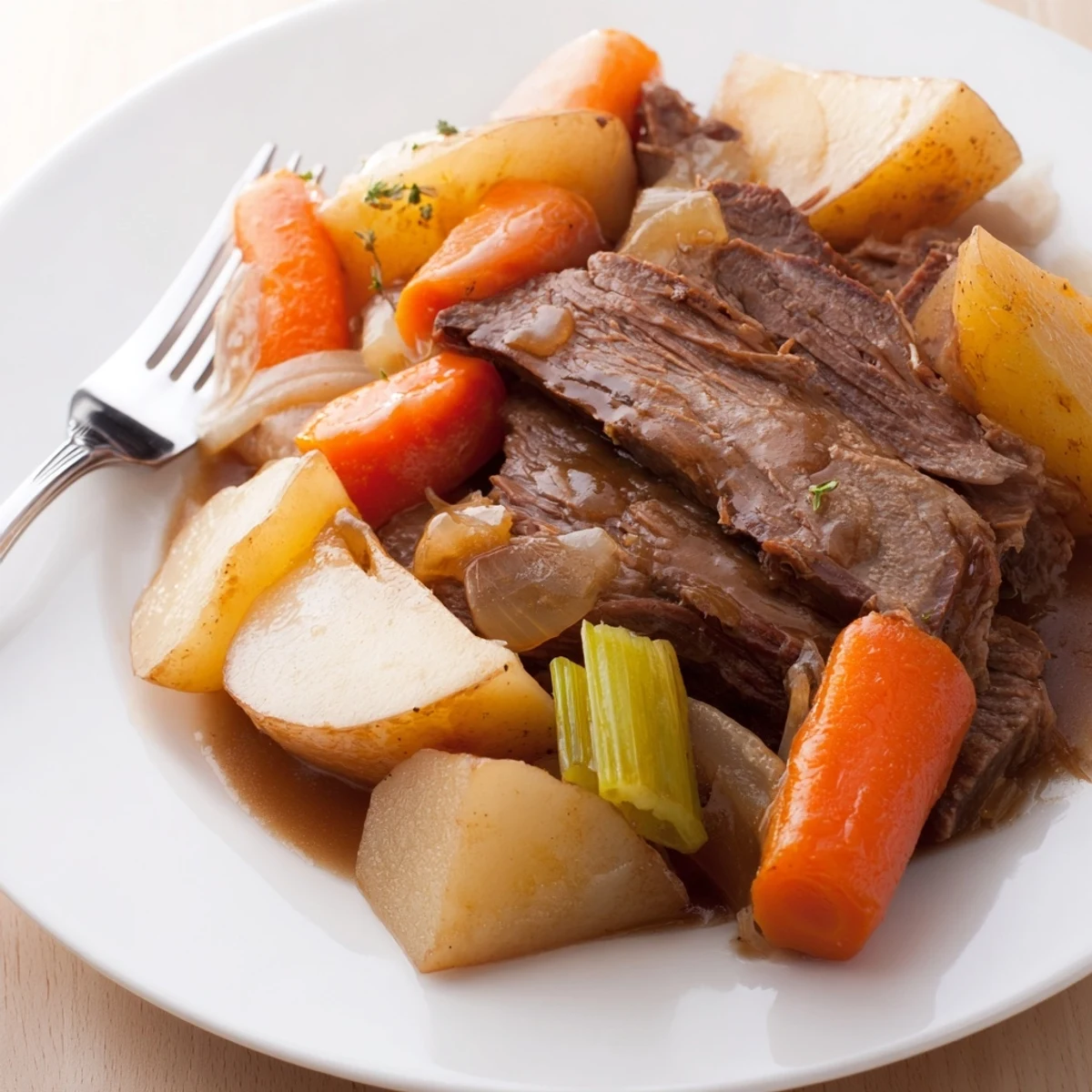Tender Slow Cooker Pot Roast served with carrots, potatoes, and rich gravy on a white platter.