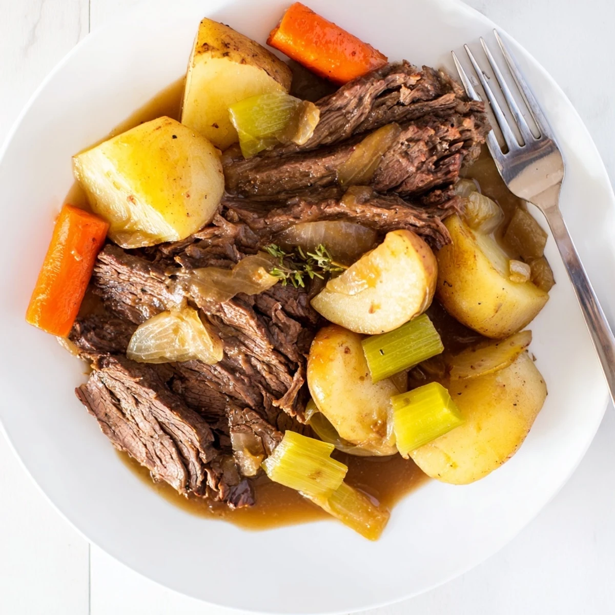 Sliced Slow Cooker Pot Roast plated with vegetables and spooned gravy, perfect for family dinner.