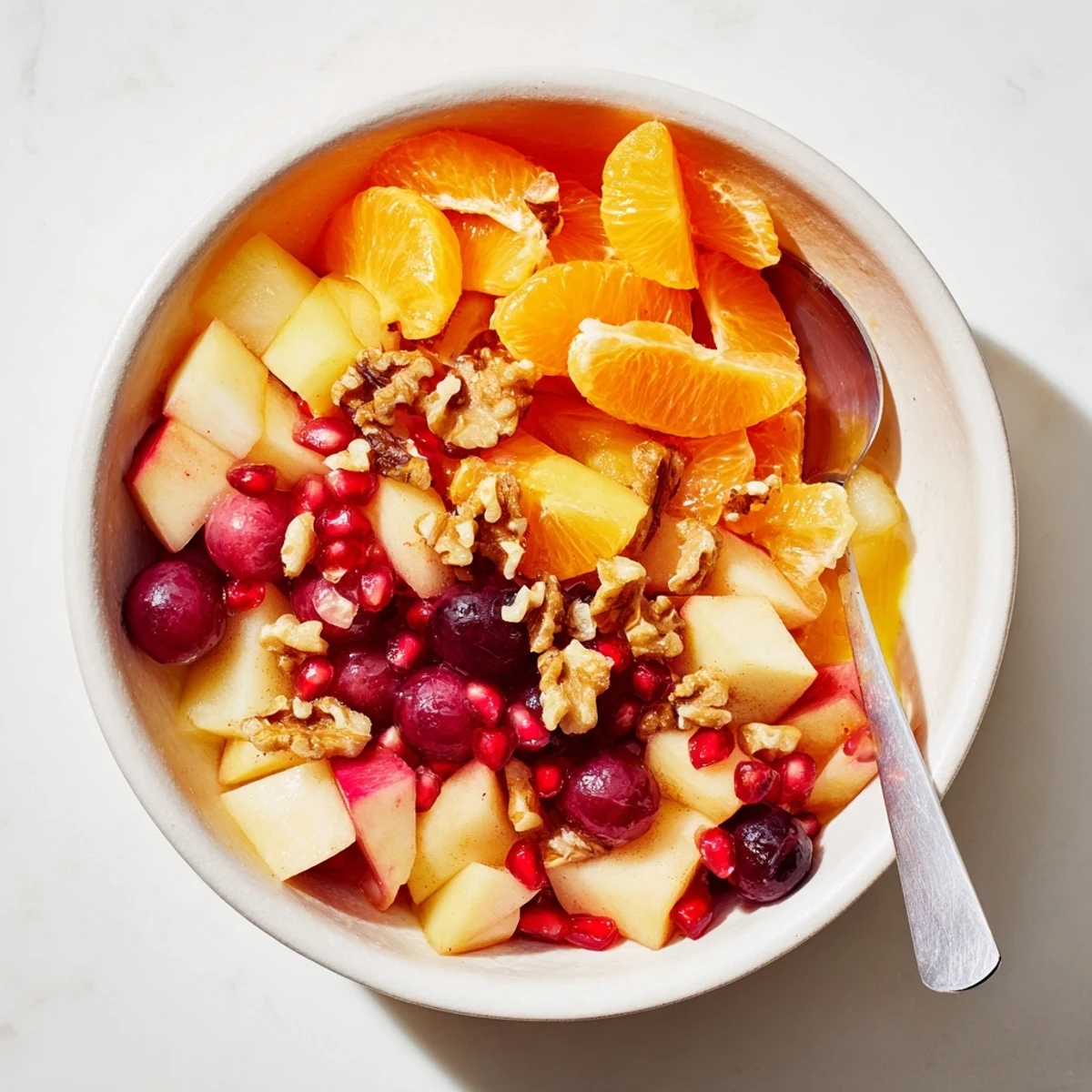 A fresh bowl of the Winter Snack Fruit Mix with diced apples and pears tossed in citrus and cinnamon, topped with optional pecans, ready to serve.