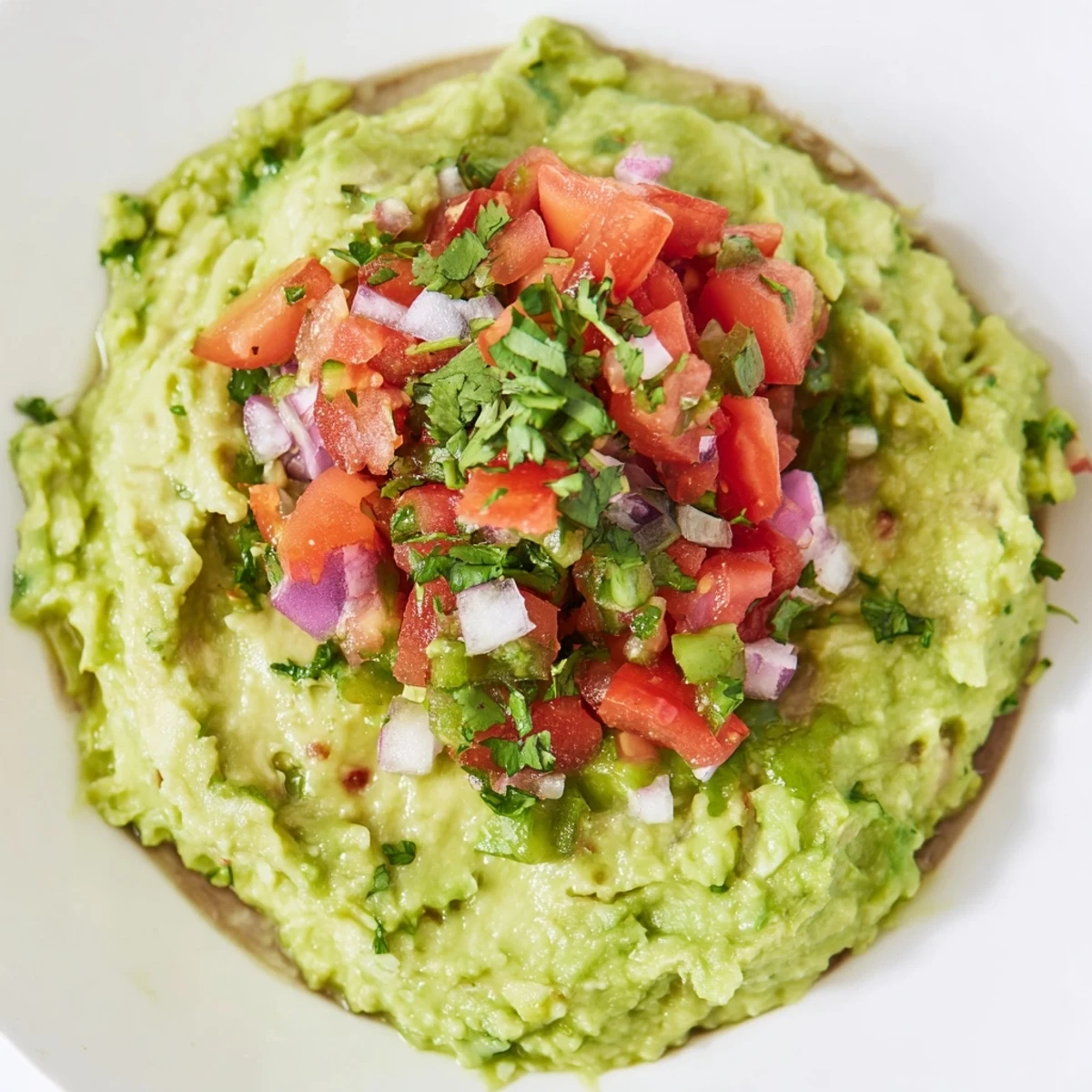 A vibrant bowl of Super Bowl Guacamole with Pico de Gallo, topped with chunky tomatoes, onions, and cilantro for game day.
