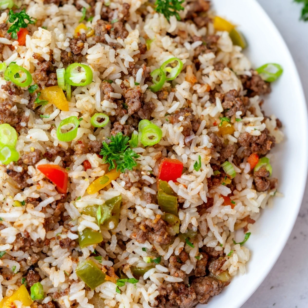 Cajun Dirty Rice with Ground Beef and Peppers steams in a skillet, mingling savory beef with vibrant red and green bell peppers.