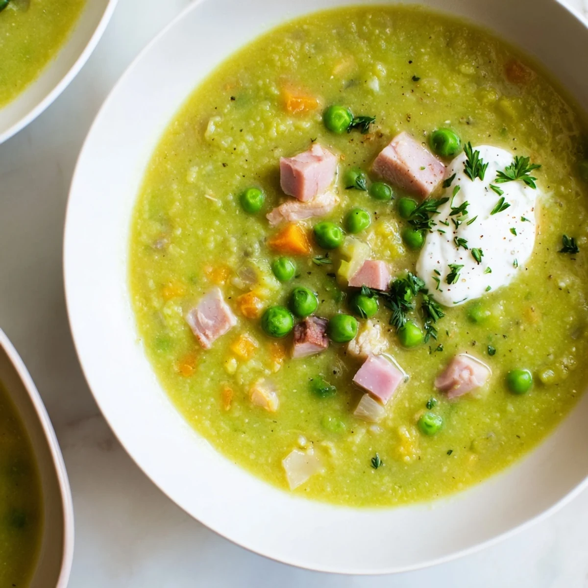 A bowl of vibrant Spring Pea Soup with Ham and Turkey, garnished with fresh parsley and a dollop of crème fraîche.