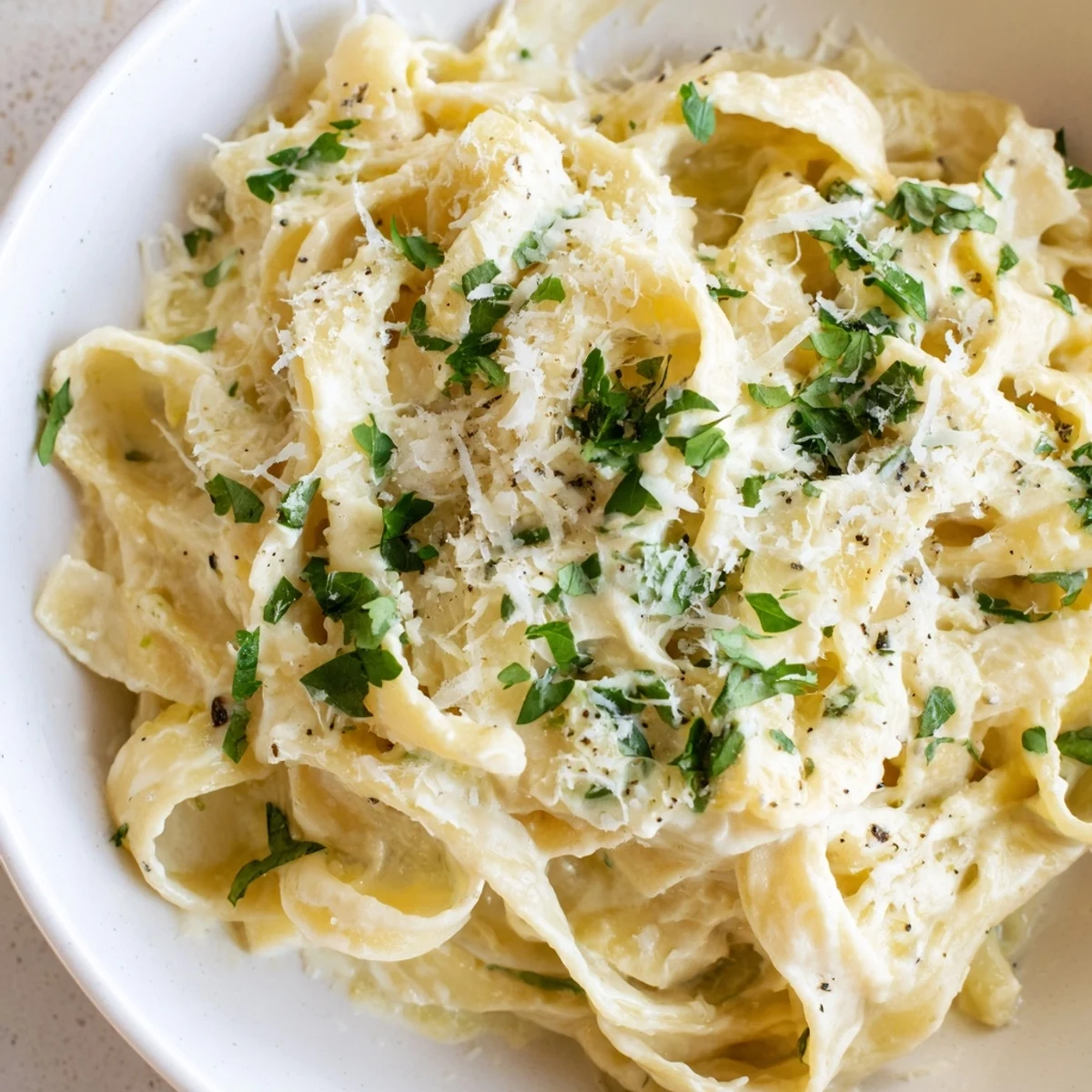 Creamy Garlic Pasta with Herbs in a white bowl, garnished with fresh parsley and basil, ready to serve.  