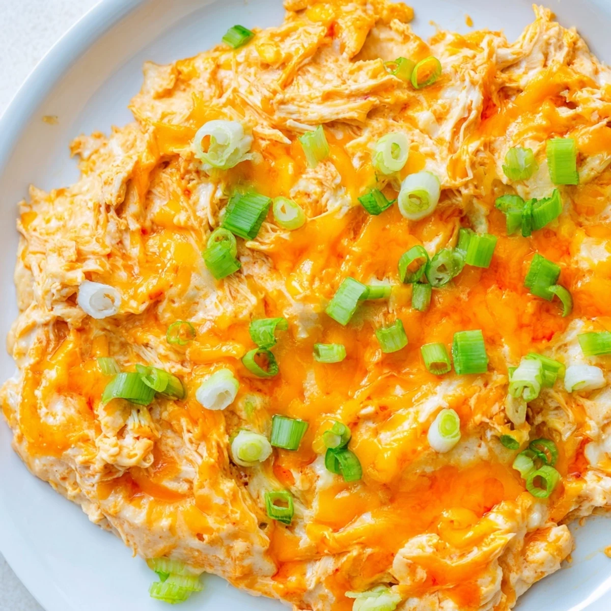 Creamy, melty Spicy Buffalo Chicken Dip baking in a dish with golden bubbles and a side of tortilla chips.