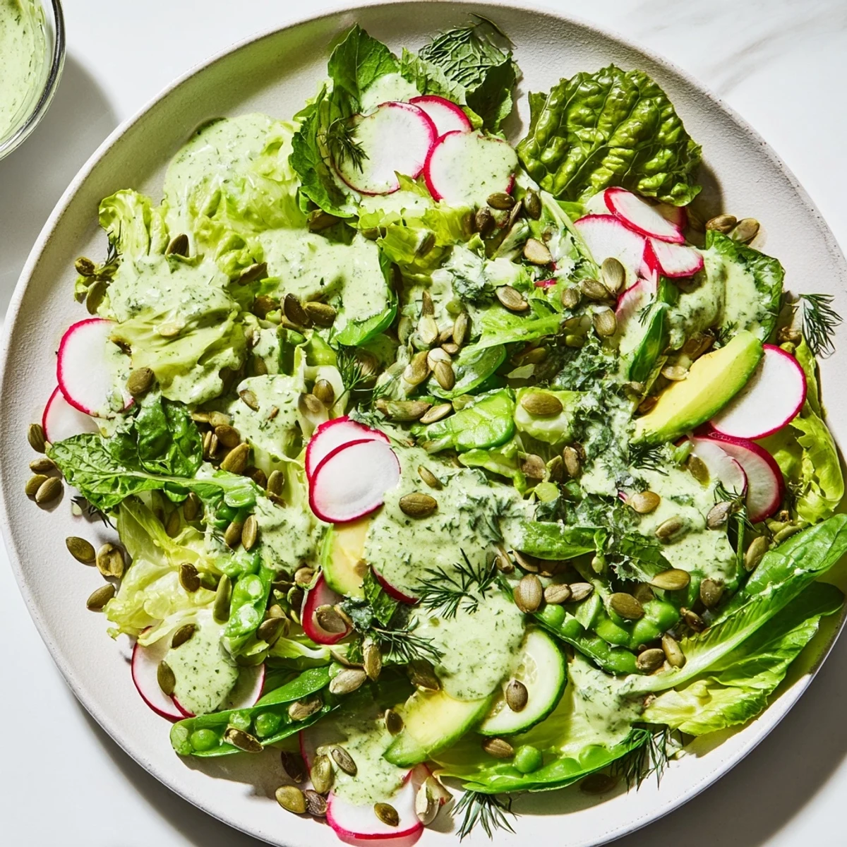 Vibrant Green Salad with Green Goddess Dressing features crunchy cucumbers, snap peas, and herbs tossed in dressing.