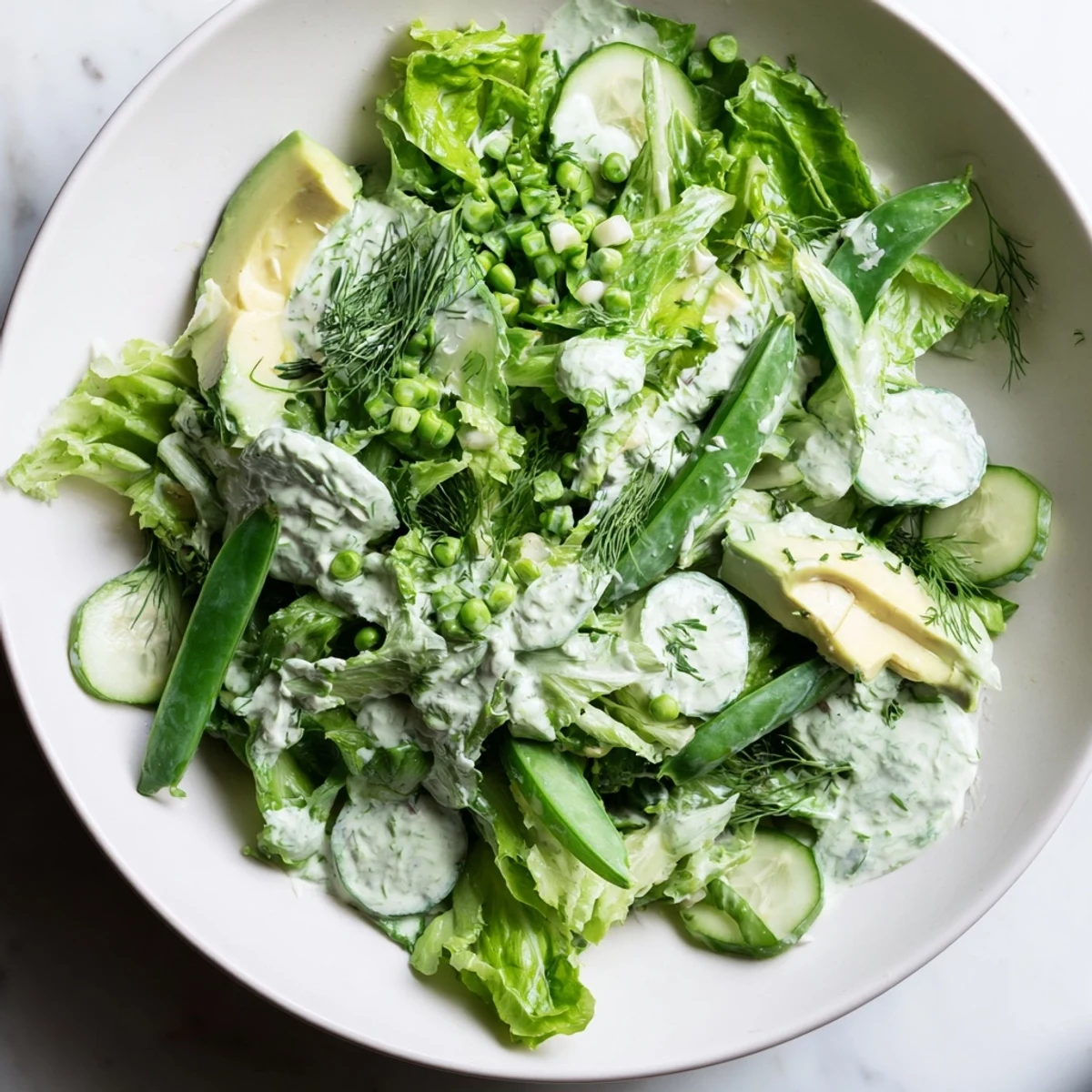 Served chilled, this Green Salad with Green Goddess Dressing features creamy avocado slices and crunchy vegetables in each bite.