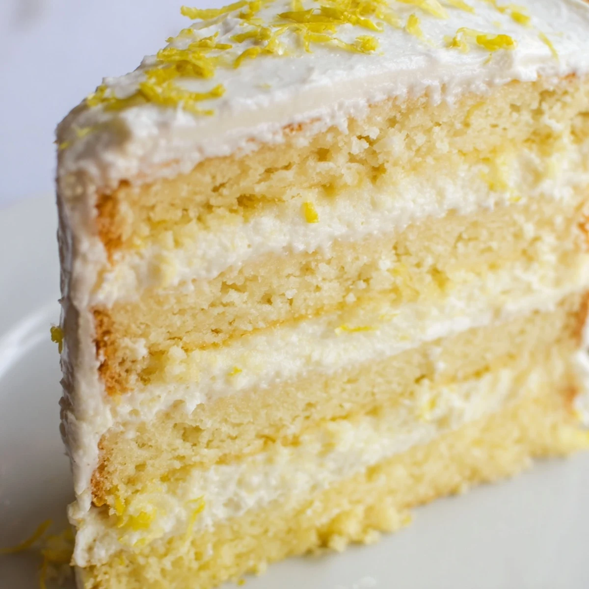 Golden layers of Limoncello Mascarpone Cake on a rustic table, showing creamy frosting and a moist sponge soaked in zesty syrup.