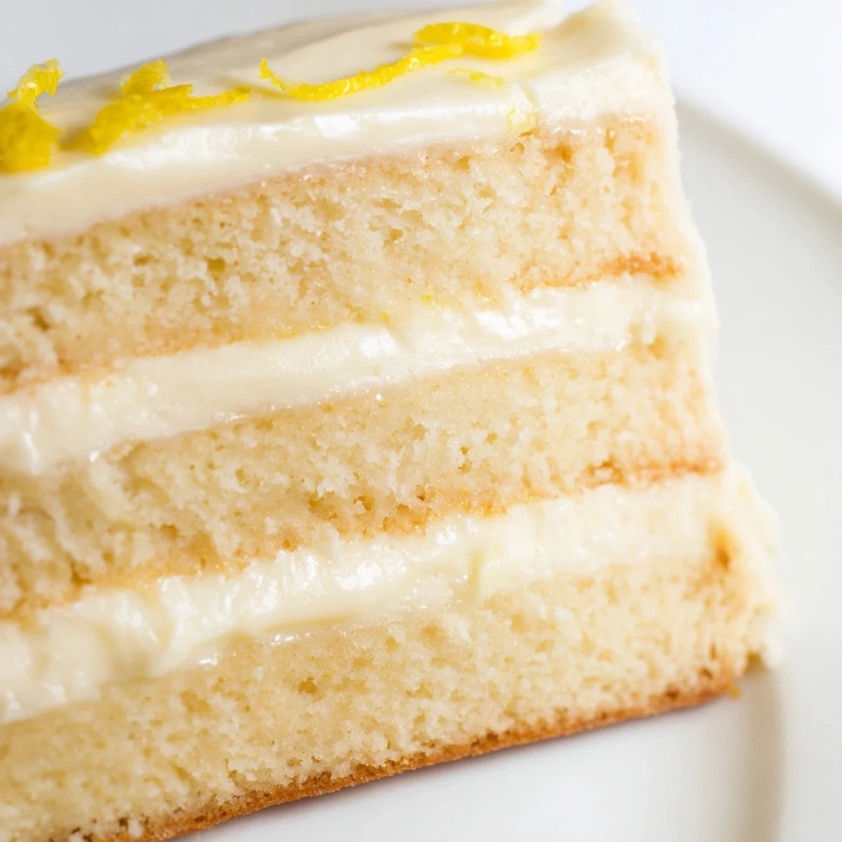 Delicious homemade Limoncello Mascarpone Cake served on a dessert plate with a drizzle of syrup and white chocolate curls.