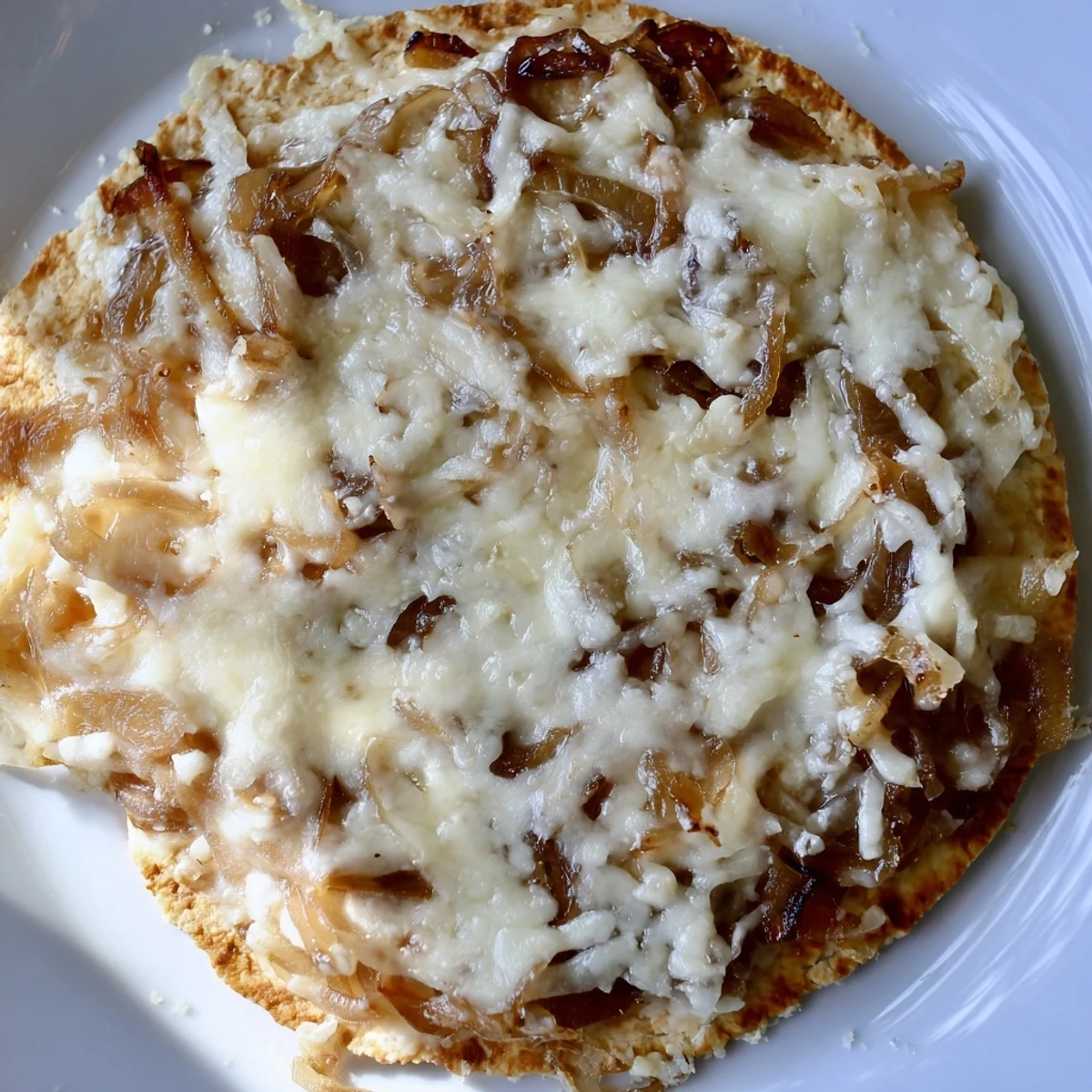 Slice of caramelized onion pizza lifted with gooey cheese stretch, placed beside a glass of red wine.