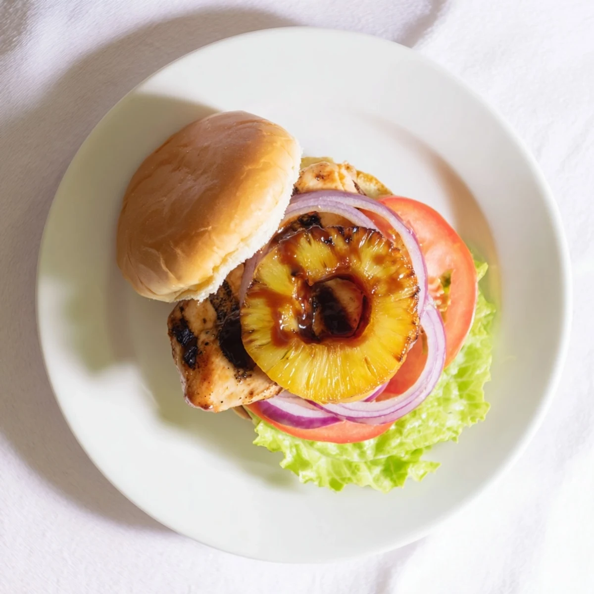 Grilled pineapple topping on a warm Hawaiian Pineapple Chicken Burger, glistening with tangy teriyaki sauce.