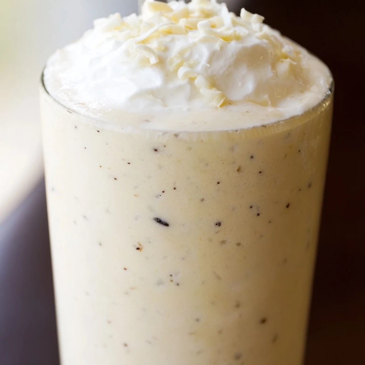 Creamy Vanilla Bean Frappuccino in a tall glass with whipped cream topping.