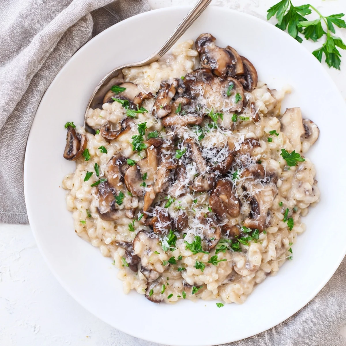 A close-up of Creamy Mushroom Risotto with earthy mushrooms and melted Parmesan in a white bowl.