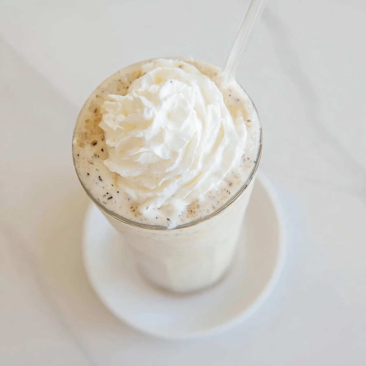 Homemade Vanilla Bean Frappuccino in a glass, highlighting the blended ice cream and milk beverage.