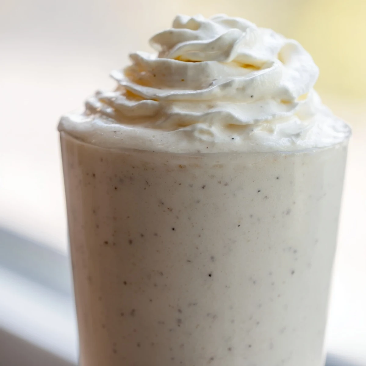 A glass of Starbucks Vanilla Bean Frappuccino topped with whipped cream shows a creamy, icy texture and rich vanilla bean flavor.