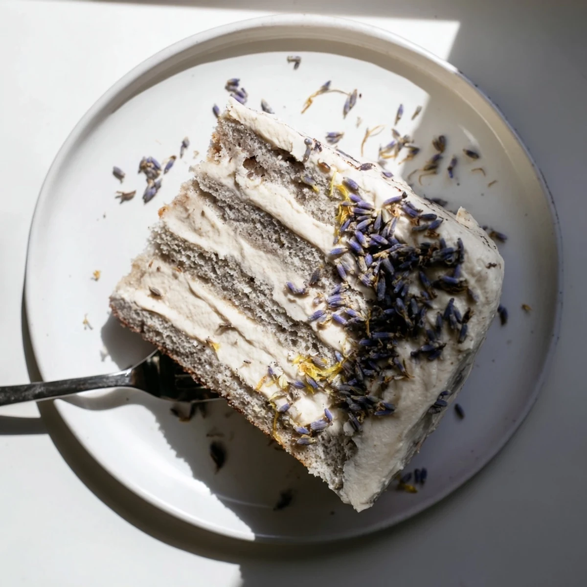 Sliced layers of London Fog Cake with Earl Grey & Lavender reveal soft crumb beside a steaming latte.