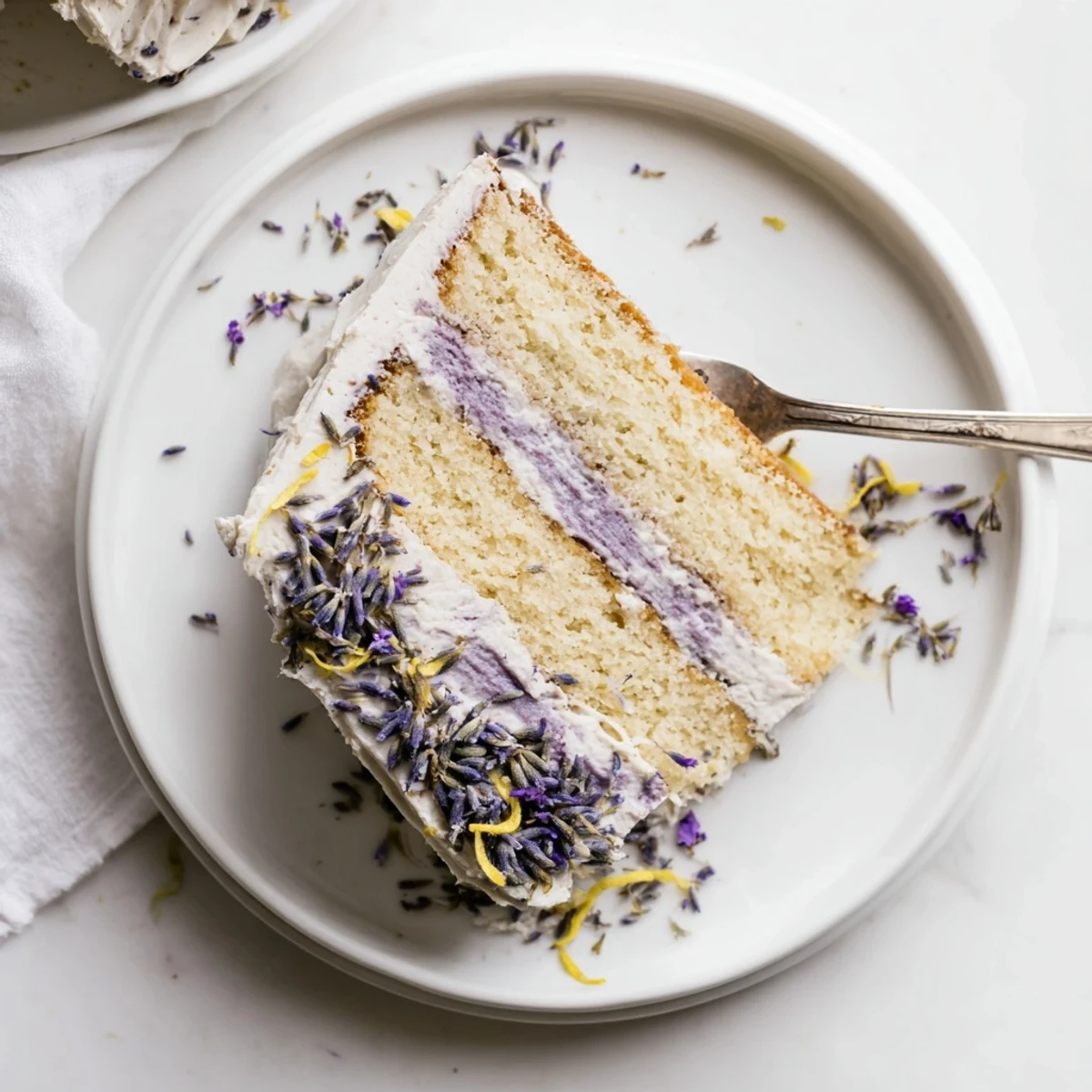 A rustic slice of London Fog Cake with Earl Grey & Lavender rests near fresh lavender buds.