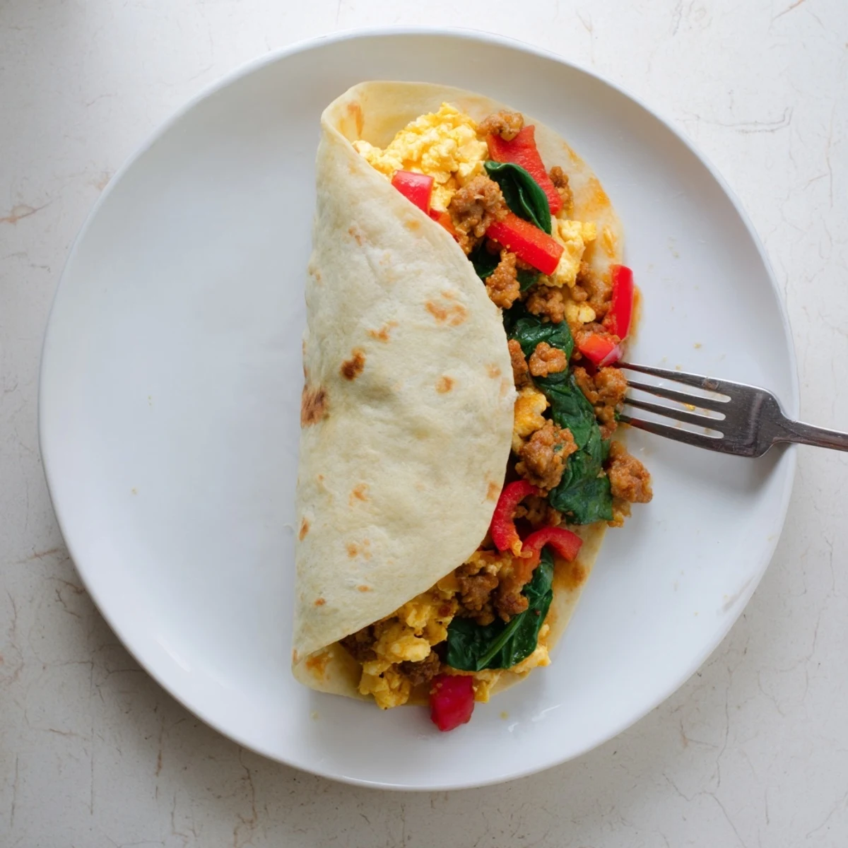 Warm flour tortillas wrapped around scrambled eggs, peppers, and cheese for easy breakfast