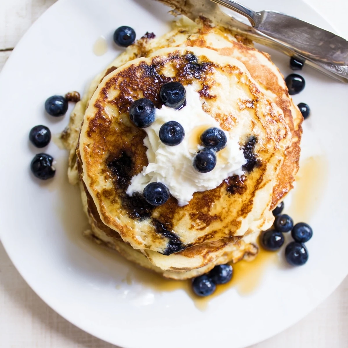 Golden brown Greek yogurt blueberry pancakes served on a white plate with melting butter