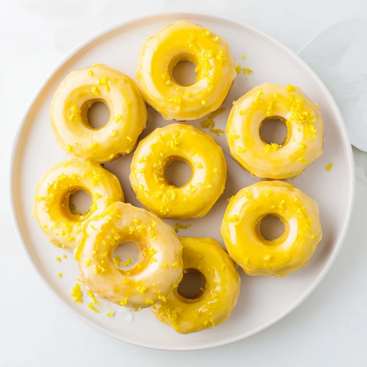 Golden gluten-free lemon mochi donuts topped with zesty lemon glaze on wire rack