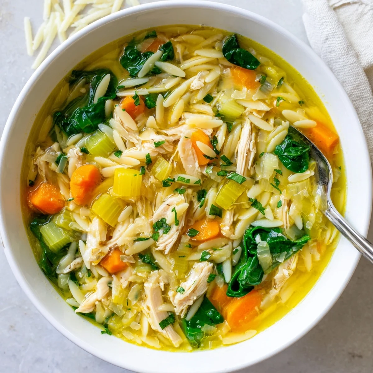 Golden bowl of Spring Lemon Chicken Orzo Soup brimming with tender chicken, vegetables, and bright lemony broth