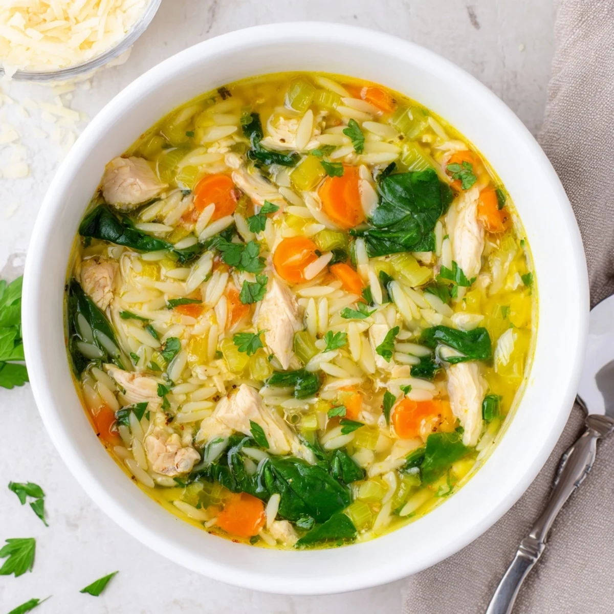 Creamy Spring Lemon Chicken Orzo Soup garnished with fresh parsley in a white soup bowl