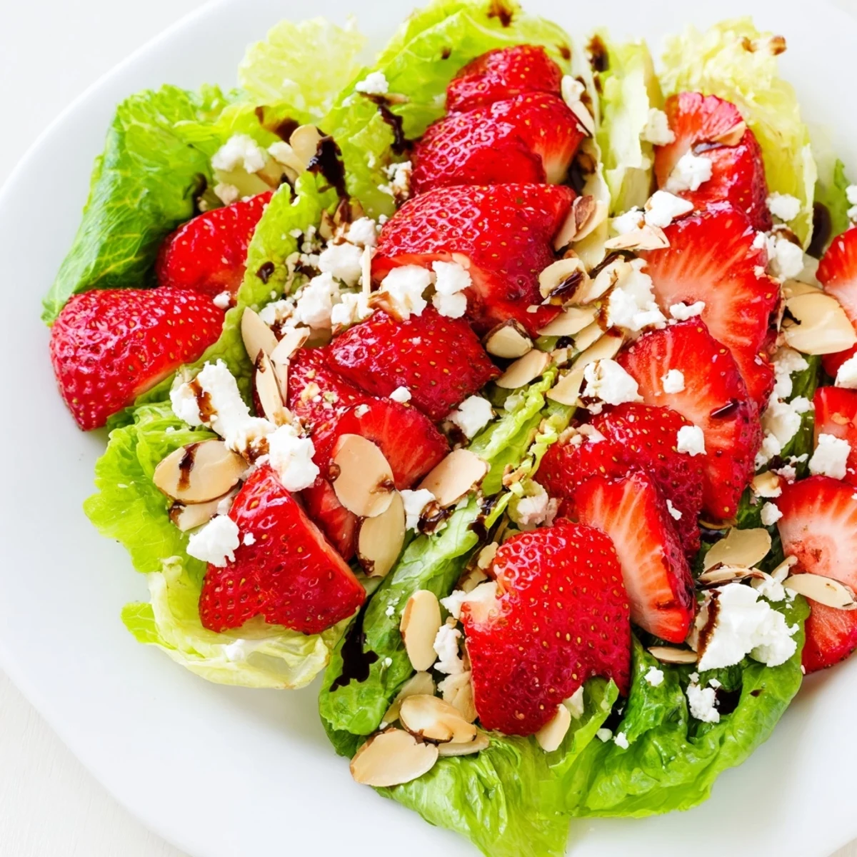 Colorful plate of strawberry romaine feta salad with sliced strawberries and crunchy almonds