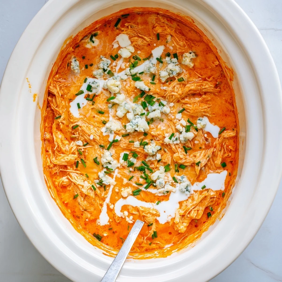 Golden slow cooker Buffalo Chicken Dip topped with fresh chives and crumbled blue cheese