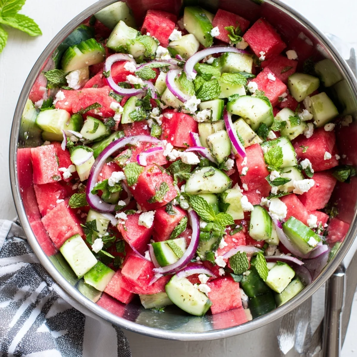 Colorful watermelon feta salad with juicy red cubes and white feta crumbles in a white bowl