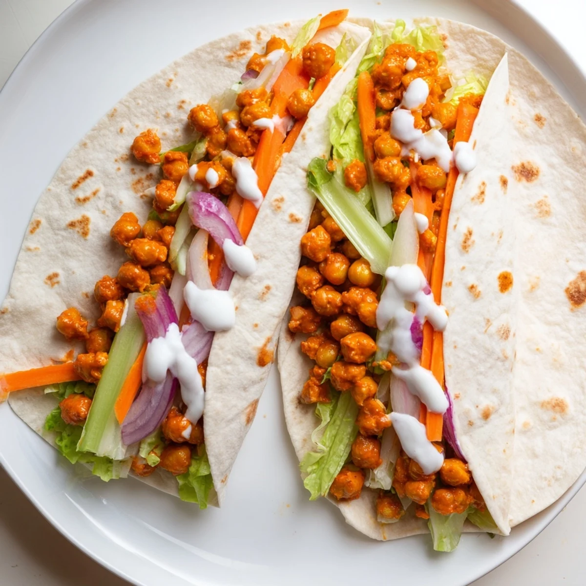 Warm buffalo chickpea wrap filled with crisp vegetables and creamy ranch dressing