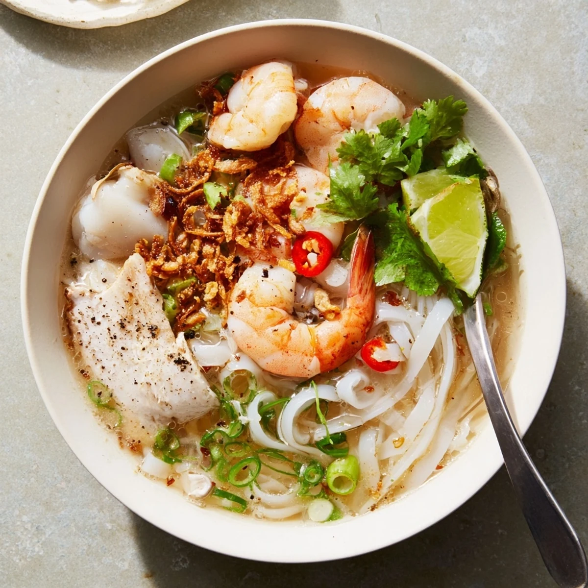 Steaming bowl of Banh Canh Cua Vietnamese crab noodle soup with thick tapioca noodles garnished with fresh cilantro and fried shallots