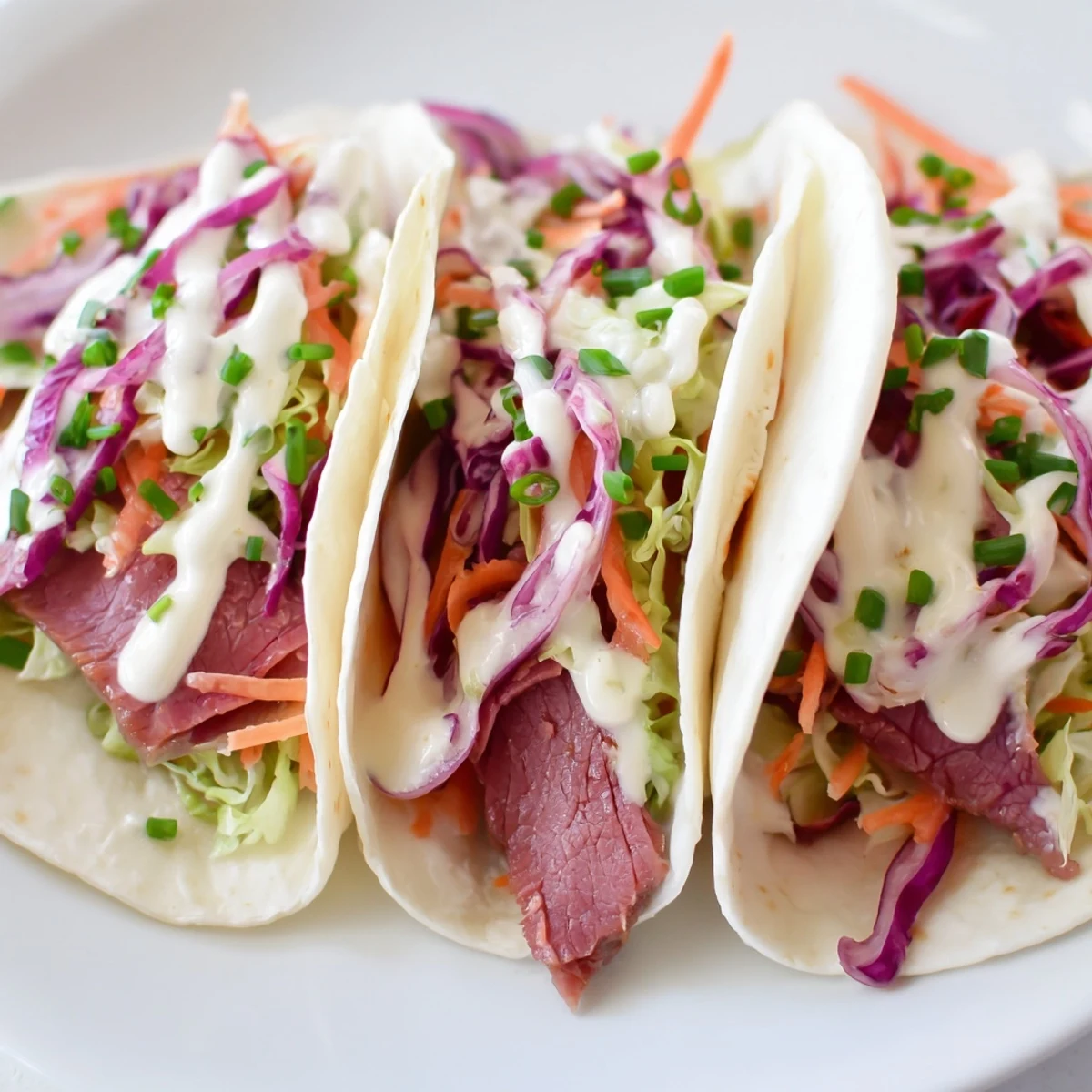 Plump Irish tacos stacked high showing layers of savory beef, colorful vegetable slaw, and zesty cream topping