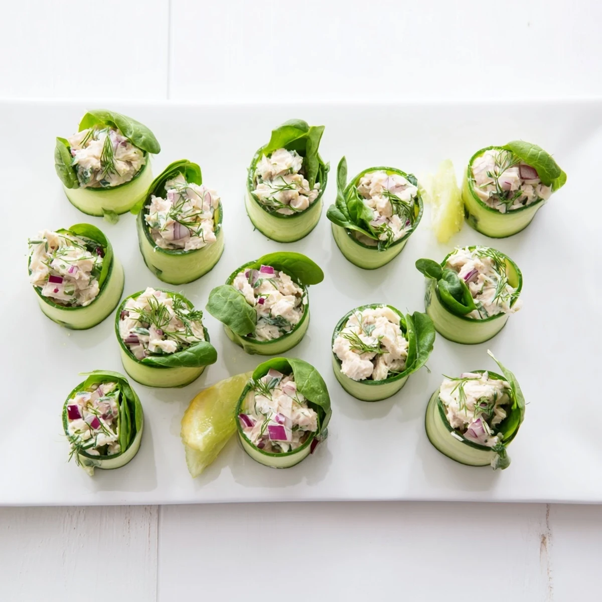 Fresh chicken salad cucumber roll ups featuring green ribbons wrapped around creamy herb-seasoned filling