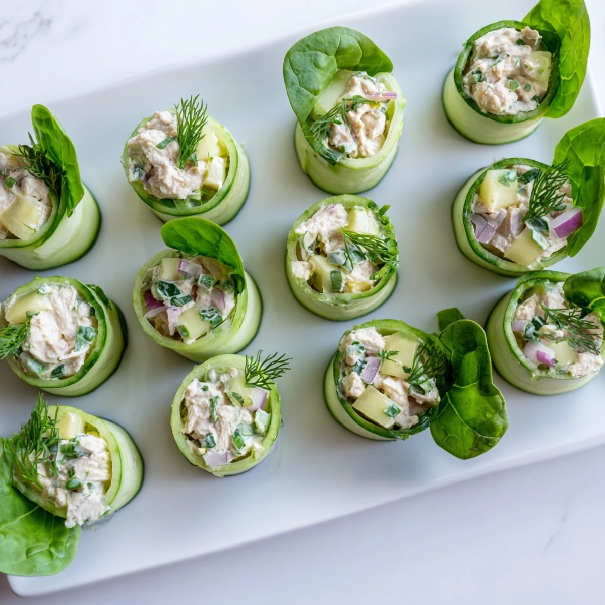 Gluten-free appetizer of rolled cucumber ribbons filled with moist chicken salad and tender celery bites