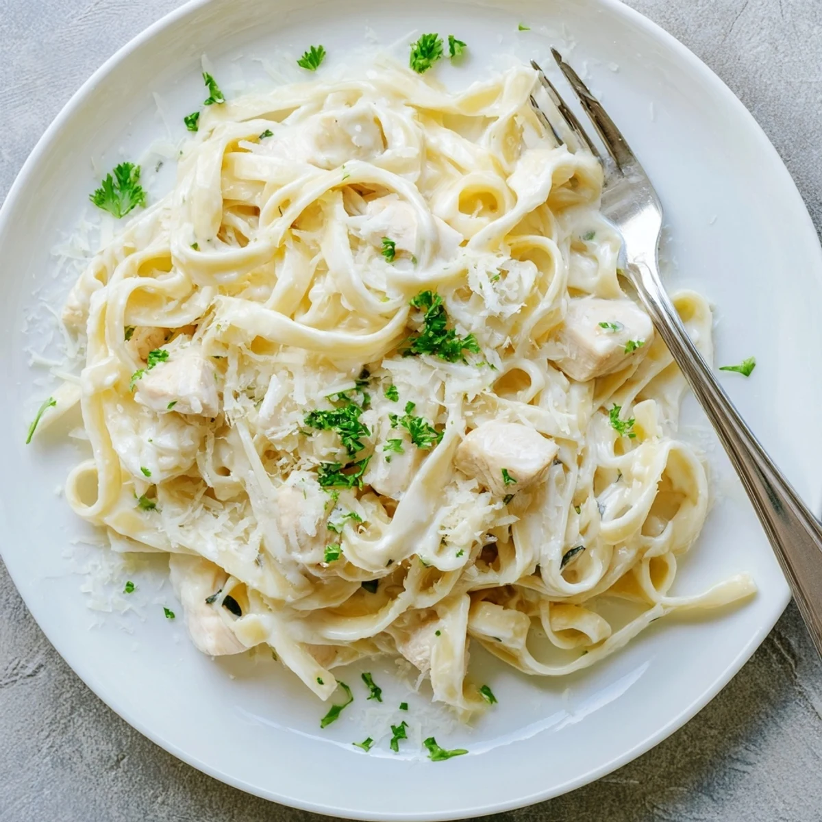 Golden chicken and al dente pasta swimming in a luscious white cheesy sauce garnished with fresh parsley