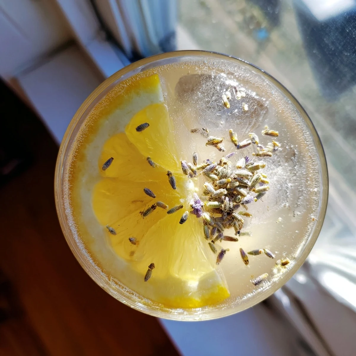 Glass pitcher of lavender lemonade garnished with fresh lemon slices and purple lavender sprigs on ice