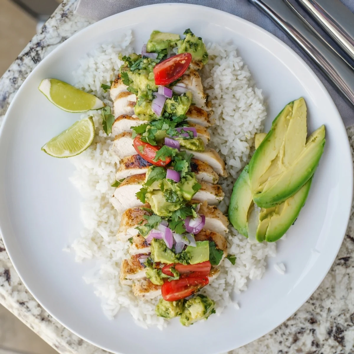 Gluten-free honey lime chicken avocado rice stack served with red onion, cherry tomatoes, and lime wedges for a zesty meal