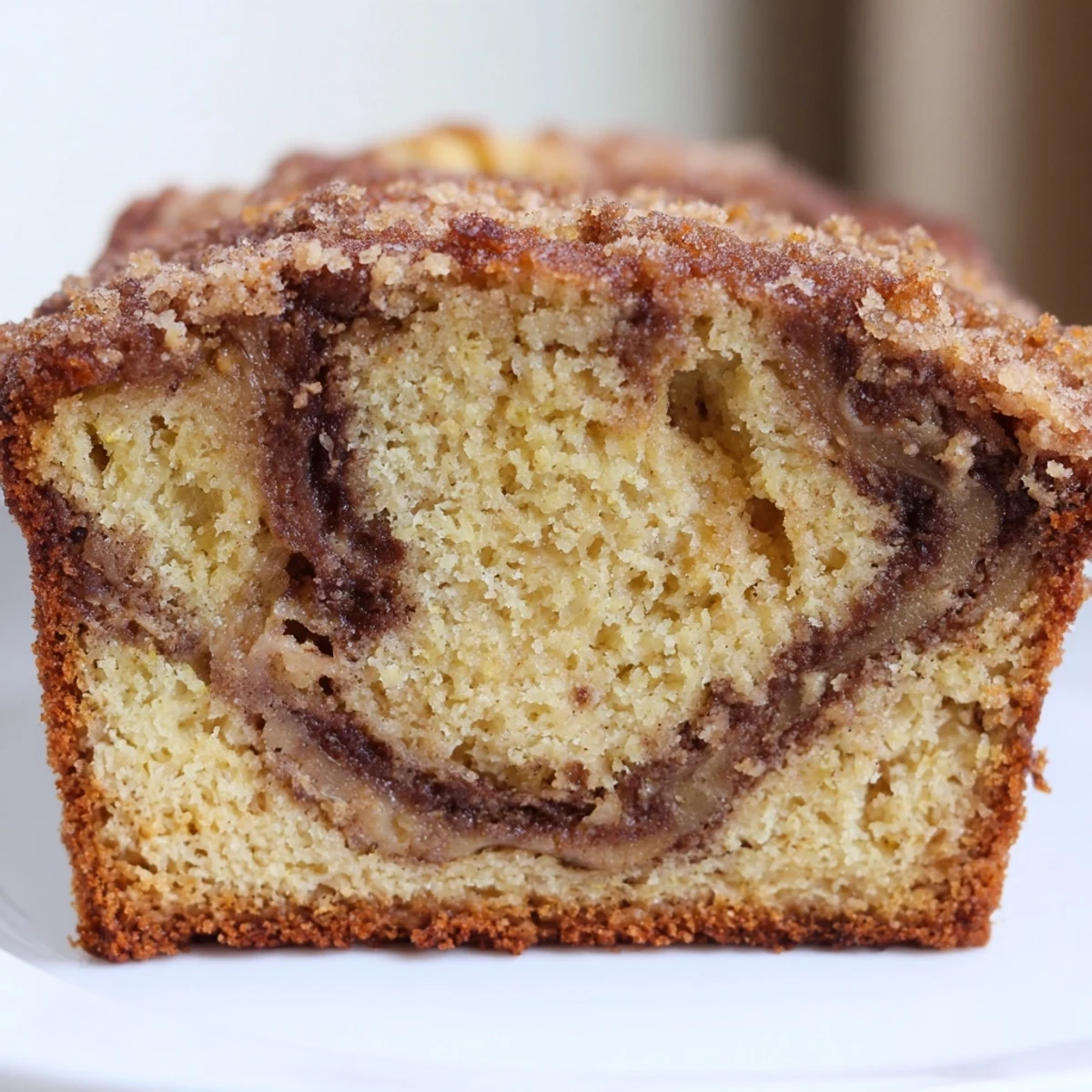 Warm slice of cinnamon sugar swirl banana bread showing marbled cinnamon ribbons throughout