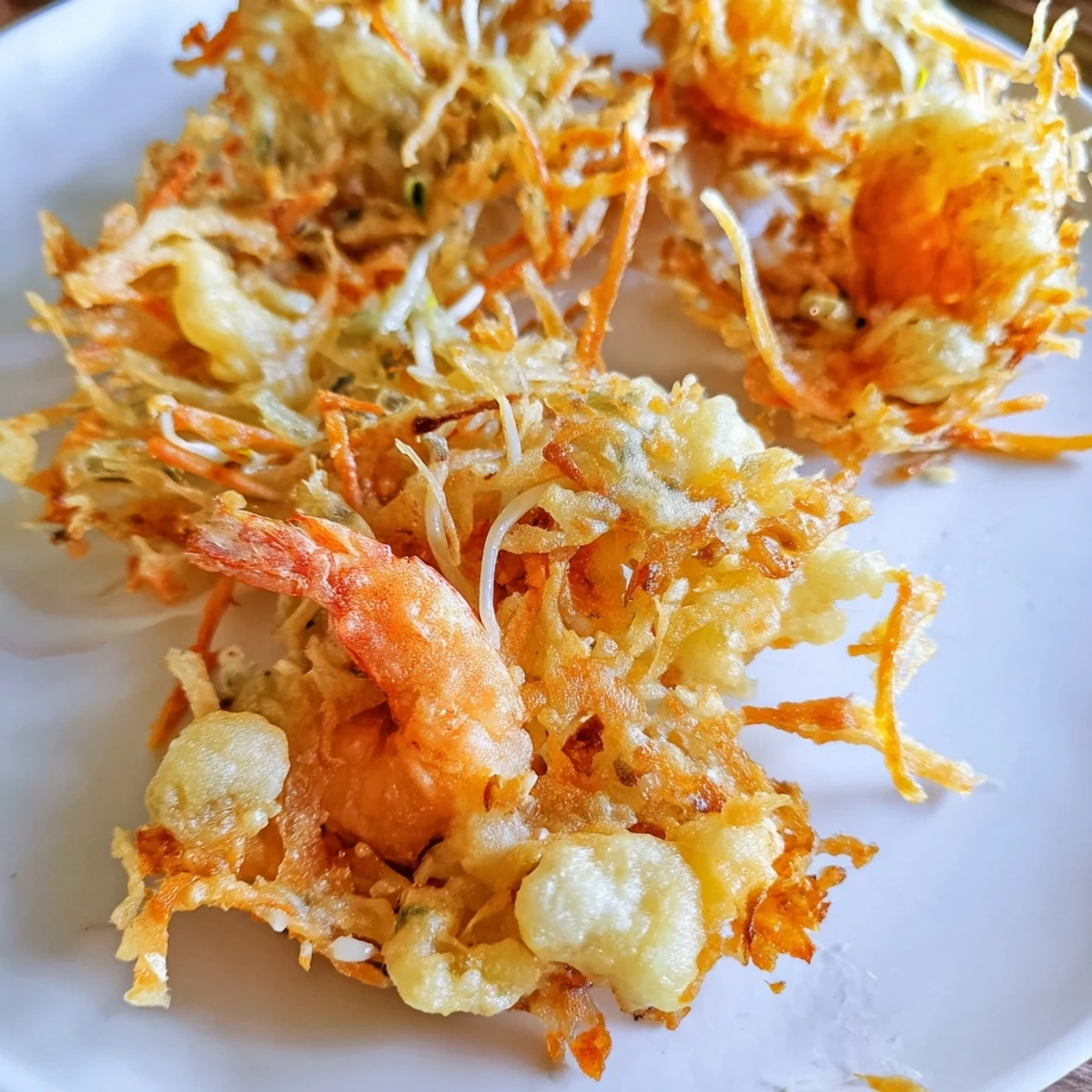 Crispy golden Ukoy Filipino shrimp fritters served with vinegar garlic dipping sauce on a white plate