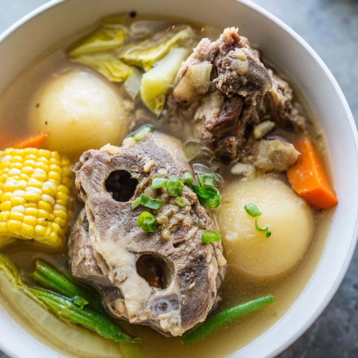 Steaming bowl of Filipino Bulalo featuring tender beef shank and bone marrow in clear broth