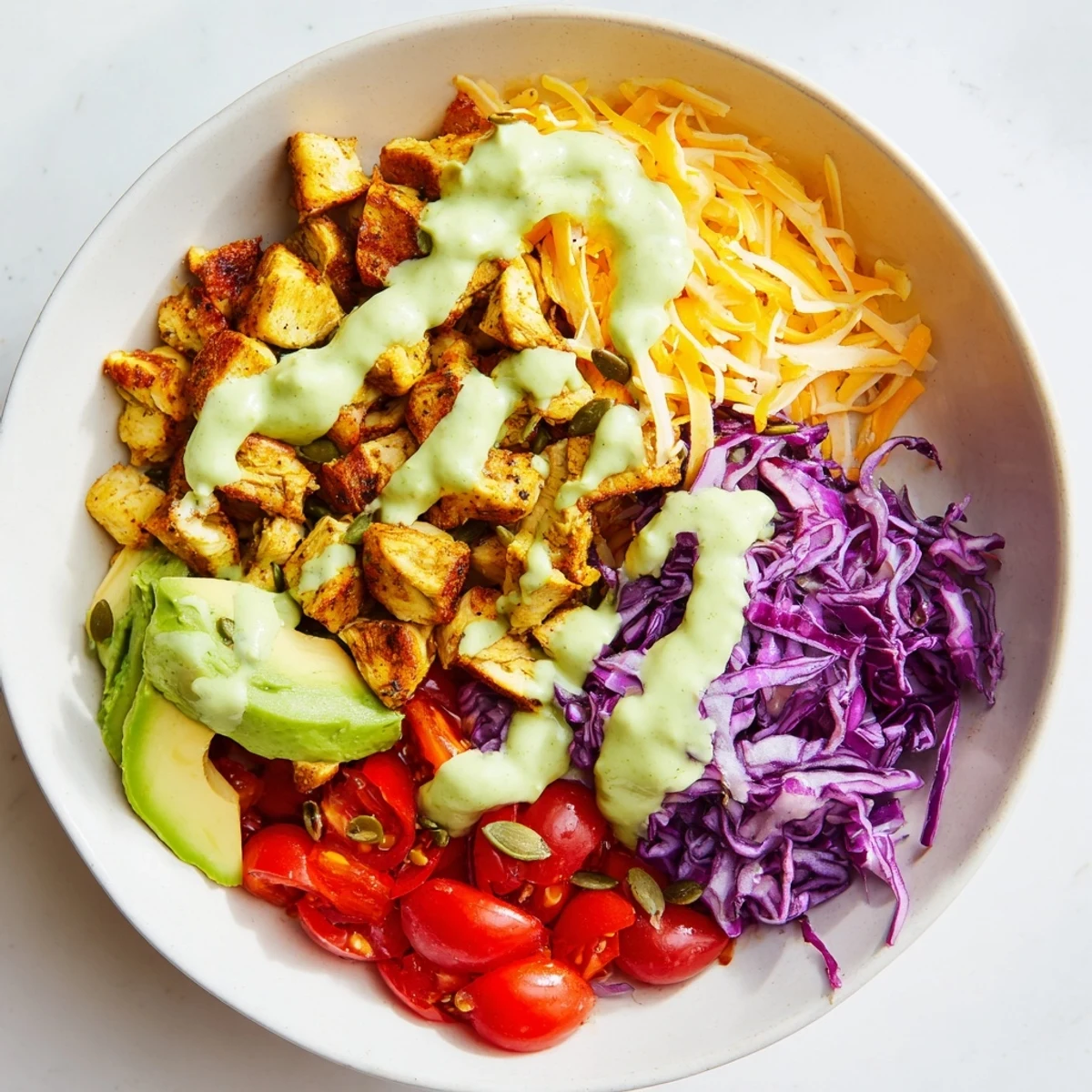 Colorful keto bowls loaded with fresh vegetables and tender seasoned chicken topped with creamy avocado dressing