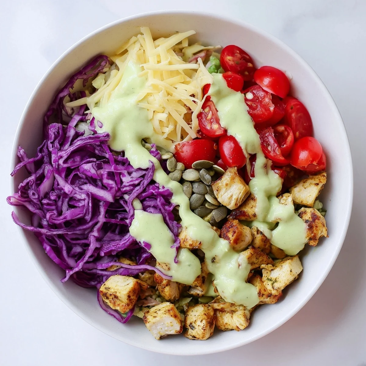 Keto bowls featuring crisp romaine lettuce, grilled chicken, and vibrant vegetables drizzled with rich avocado sauce