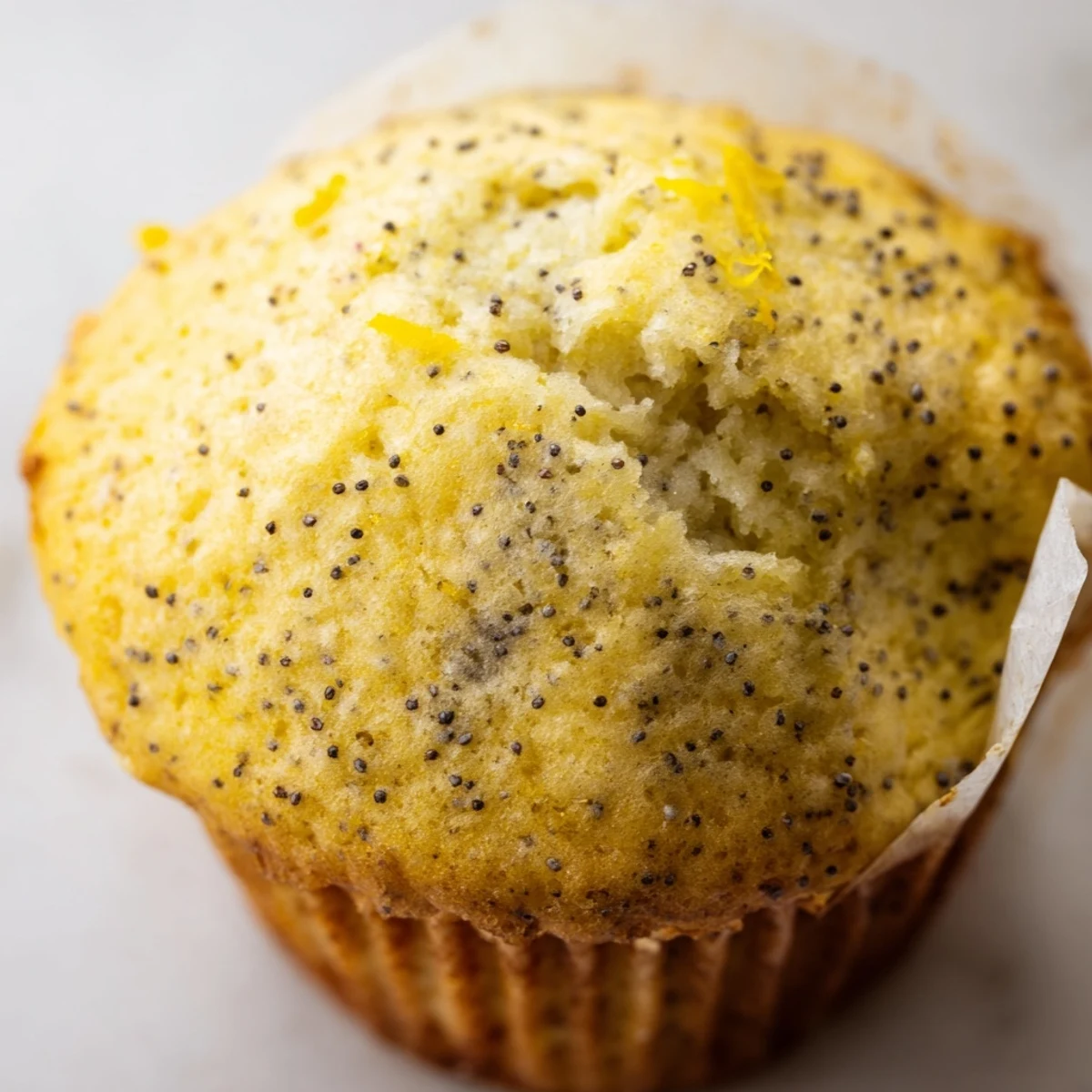 Golden lemon poppy seed muffins with domed tops cooling on a wire rack