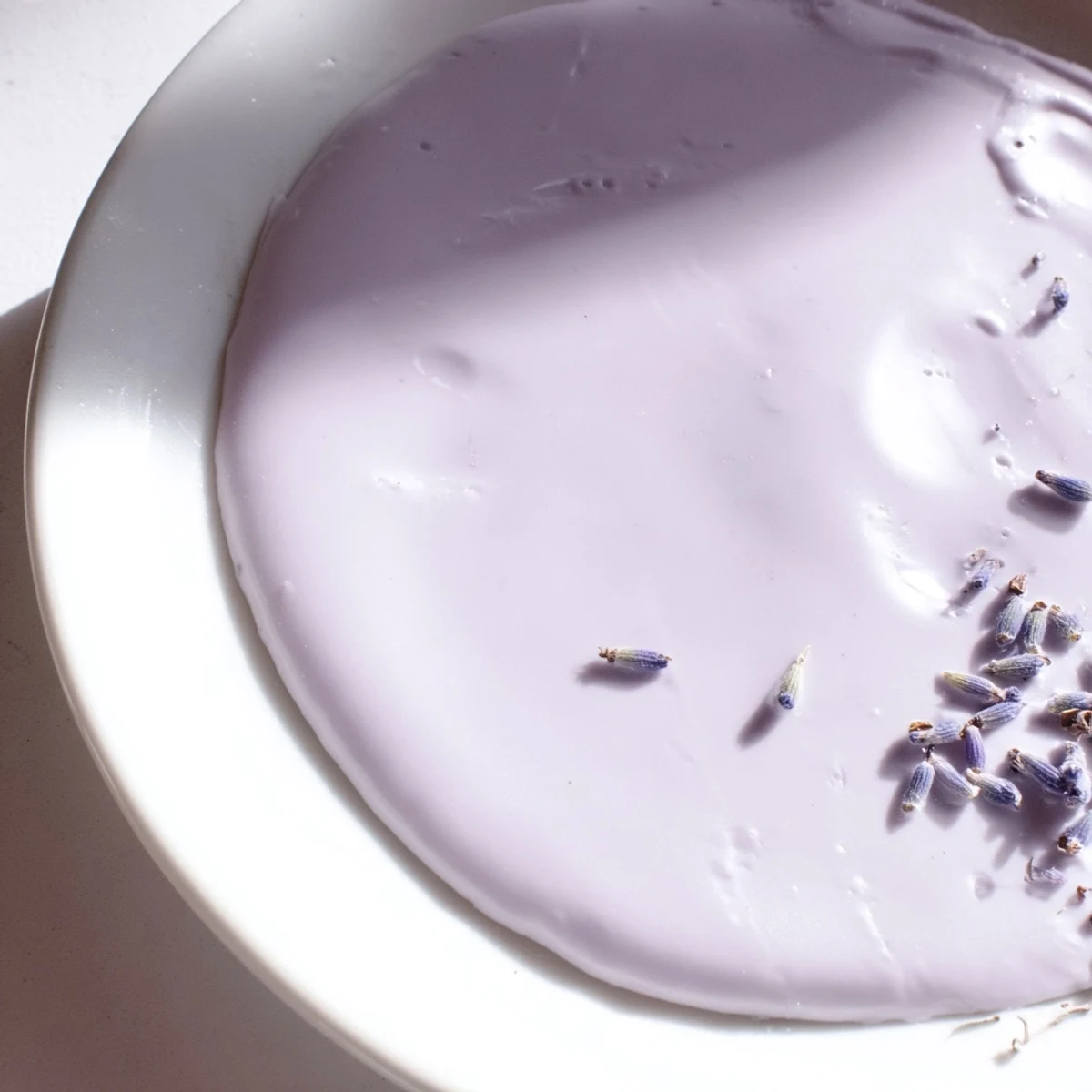 Glossy purple-tinged lavender glaze pooled on a white ceramic plate ready for drizzling