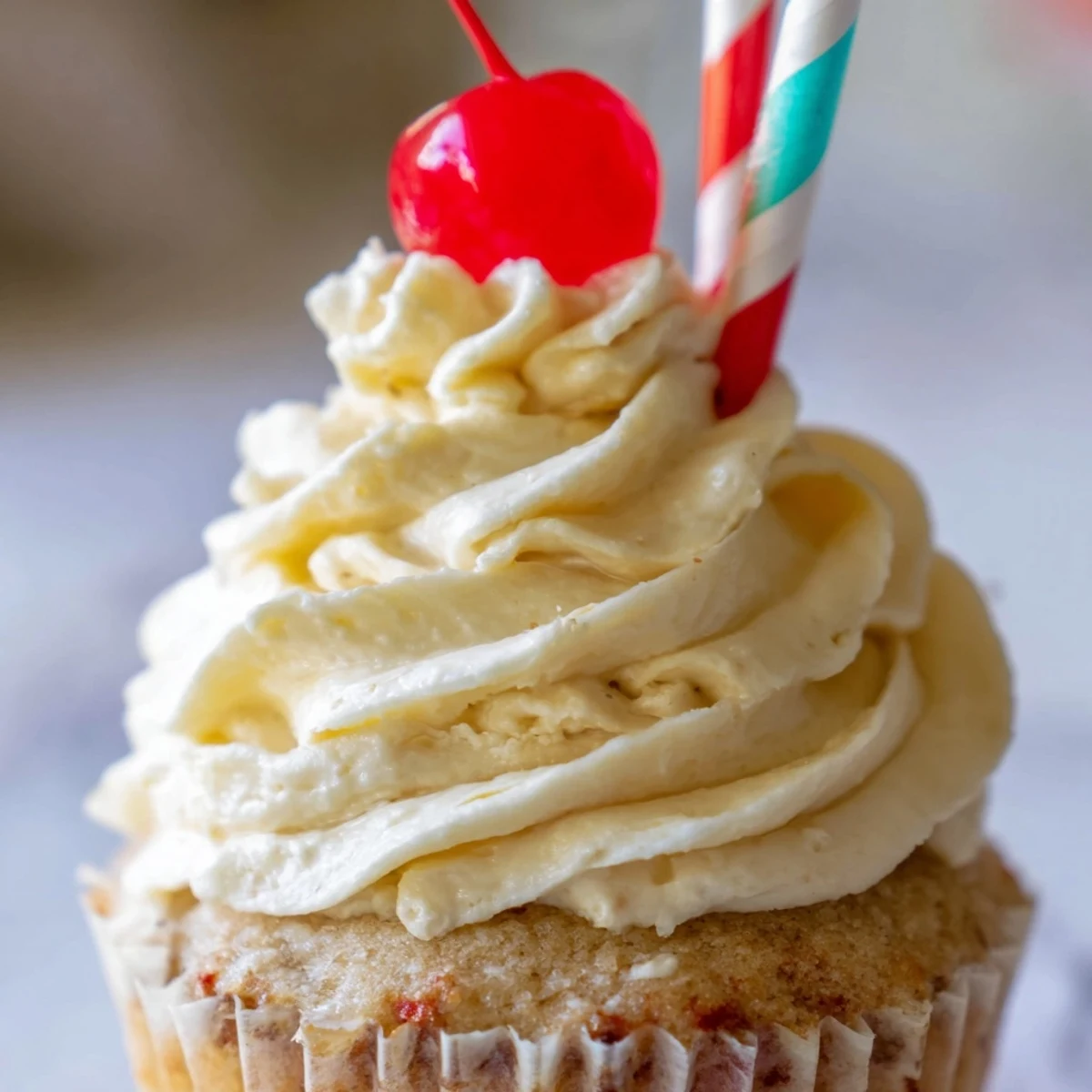 Moist banana milkshake cupcakes topped with creamy vanilla frosting and bright red maraschino cherries