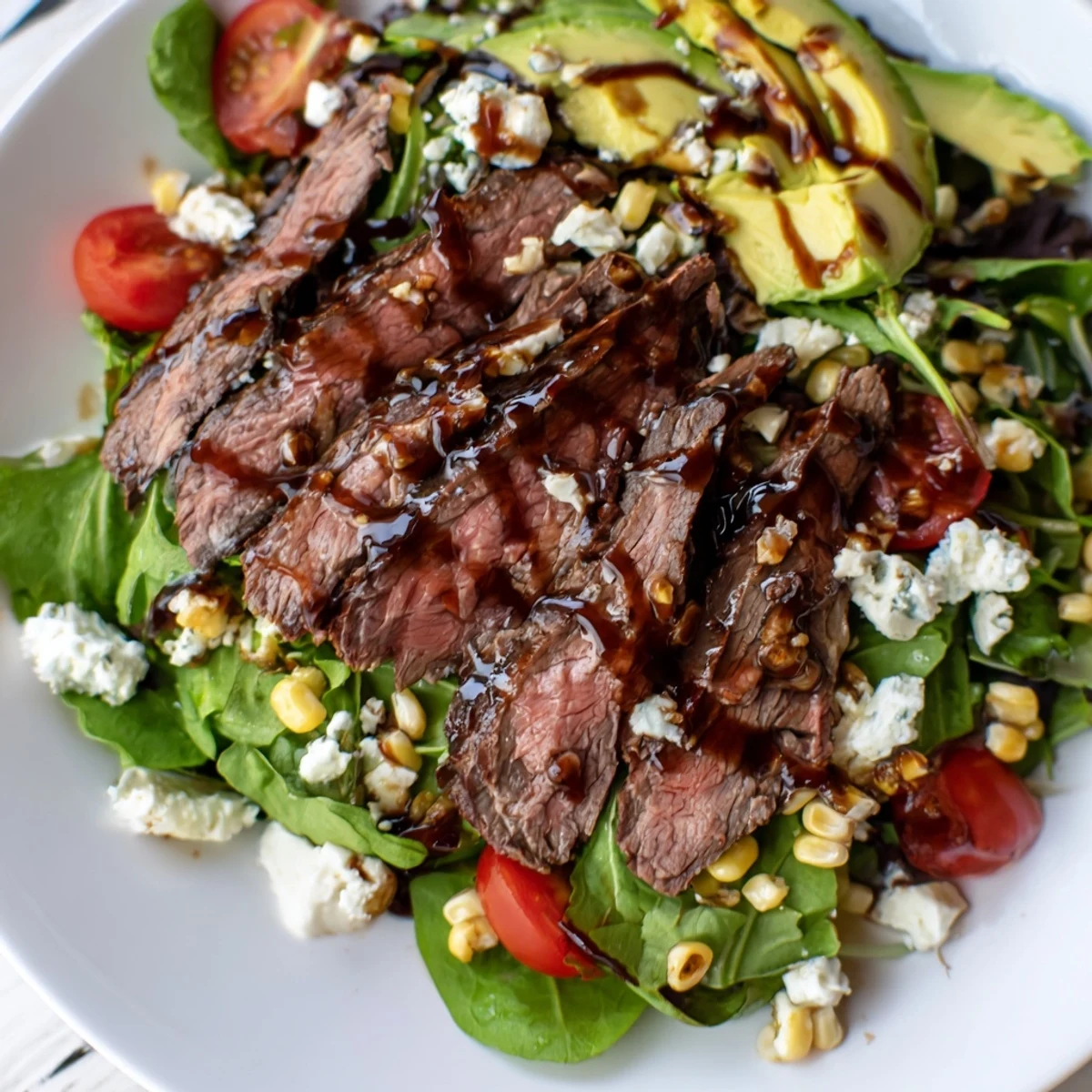 Juicy grilled steak and charred corn atop mixed greens in a balsamic steak Gorgonzola salad