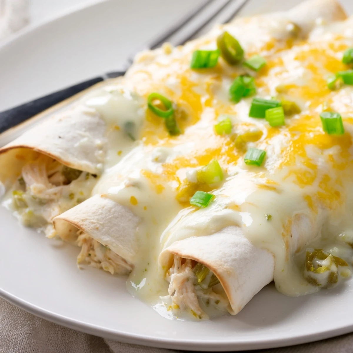 Creamy White Chicken Enchiladas steaming under bubbly golden cheese, garnished with cilantro.