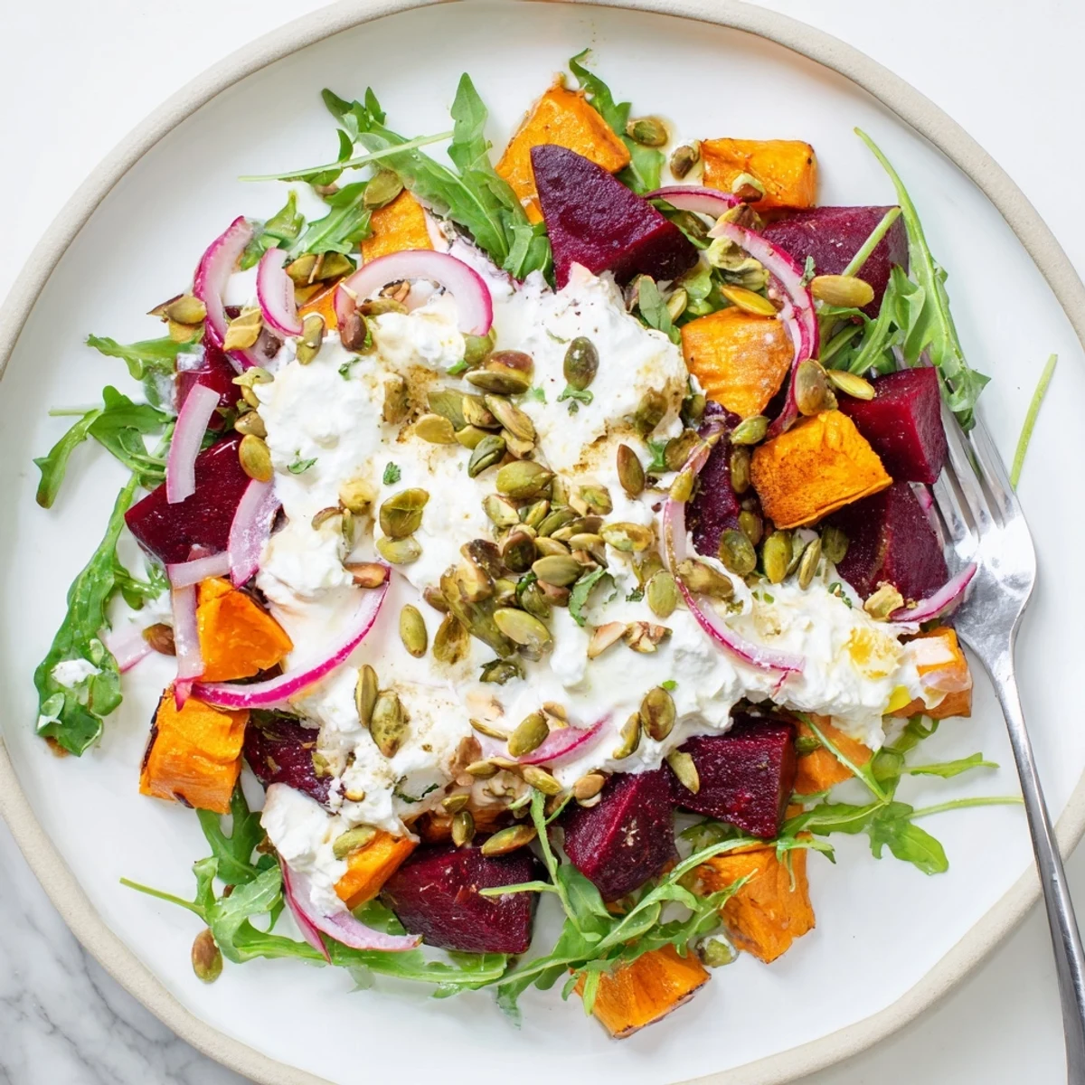 Creamy Roasted Beet Salad With Sweet Potato Feta on arugula, crunchy toasted seeds.